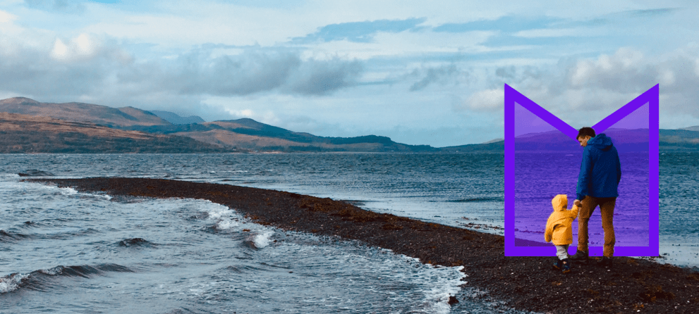 A man and young child walking on the beach. They're highlighted by an M-shaped purple graphic.